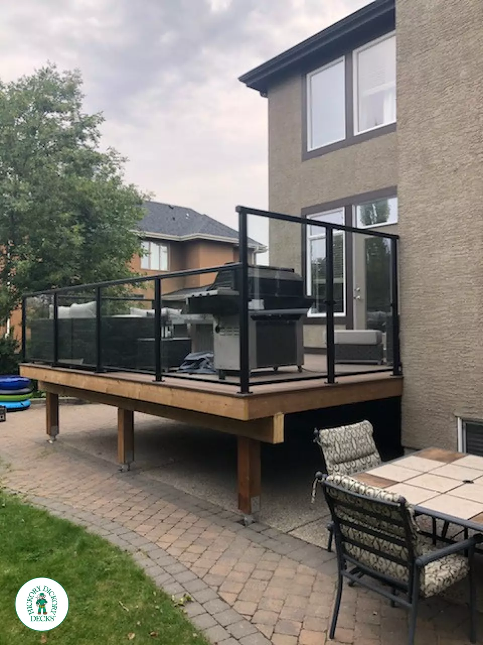 Mid high brown Dekorators deck with steps leading to back yard and glass railings.