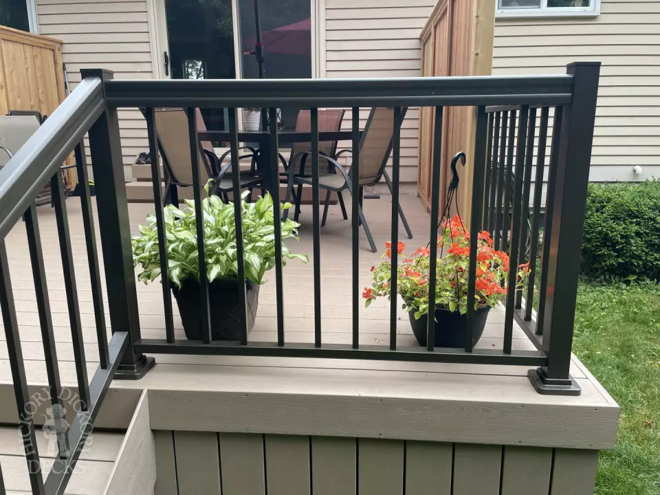 Small CLubhouse deck with four steps leading to backyard, black aluminum railing, and a cedar privacy screen.