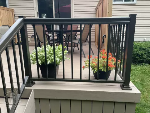 Small CLubhouse deck with four steps leading to backyard, black aluminum railing, and a cedar privacy screen.