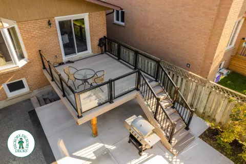 Mid rise grey composite deck with glass railings and a dark grey border.