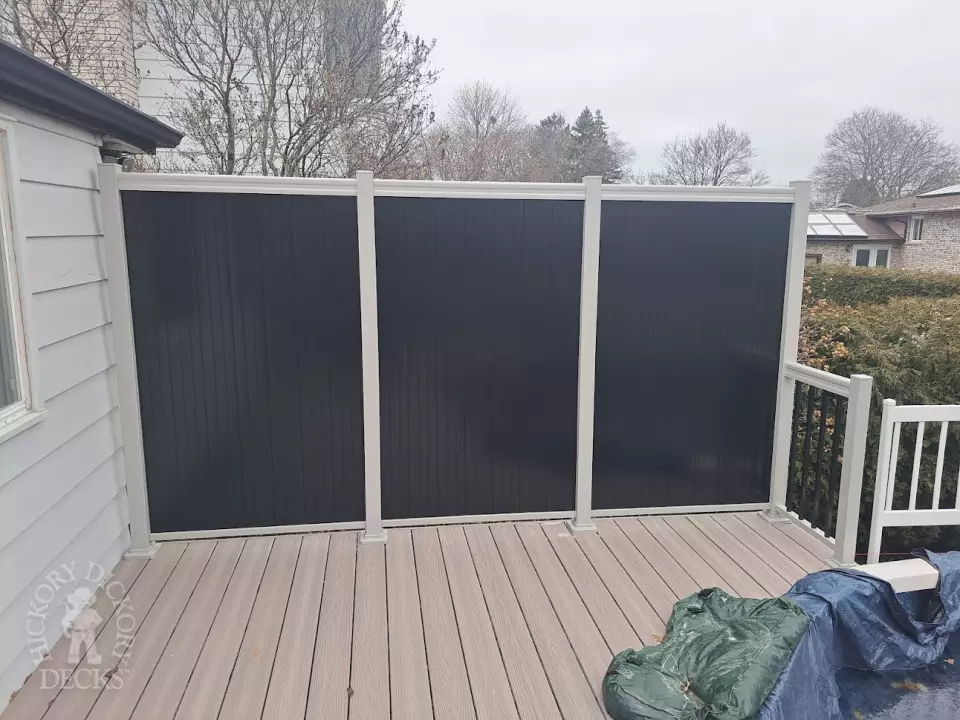 Two level grey Fiberon deck with beige picket aluminum railing and the top level surrounding an above ground pool.