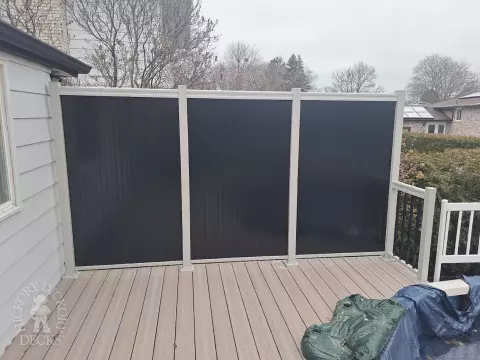 Two level grey Fiberon deck with beige picket aluminum railing and the top level surrounding an above ground pool.
