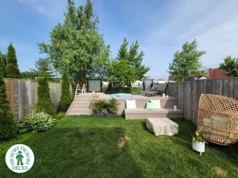 Grey Fiberon deck surrounding above ground pool with smoked glass railing.
