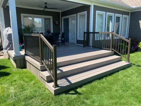 Small covered grey composite porch with aluminum railing.
