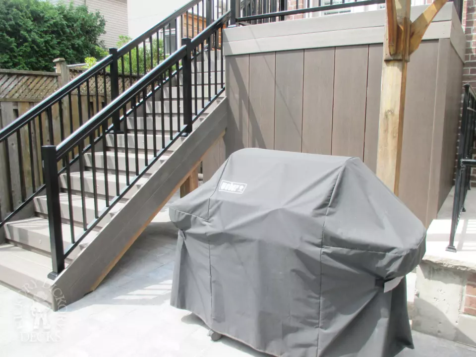 Elevated grey clubhouse deck with black aluminum railing and lights in steps.