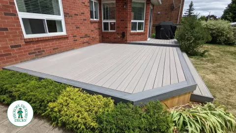 Grey composite deck with dark grey border, cedar skirt, and aluminum picket railing.