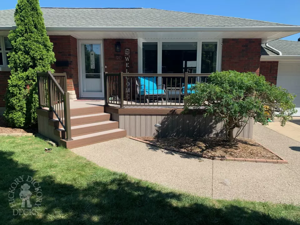 Grey front porch with brown trim and brown aluminum railing.