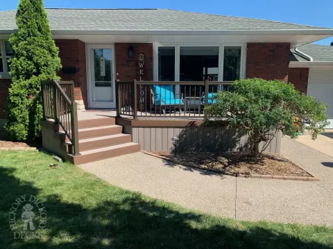 Grey front porch with brown trim and brown aluminum railing.