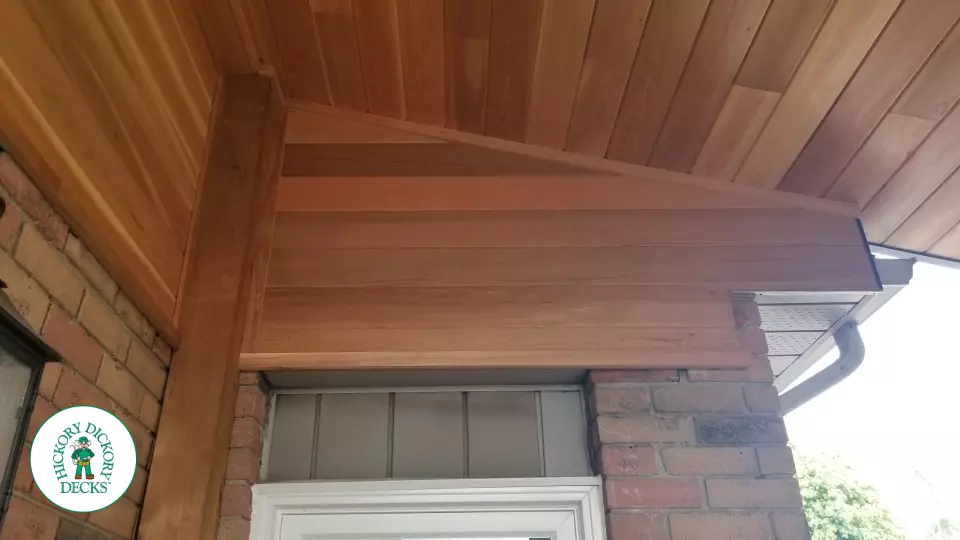 Low brown Veka deck with custom roof structure, black aluminum railing, and lights in steps.