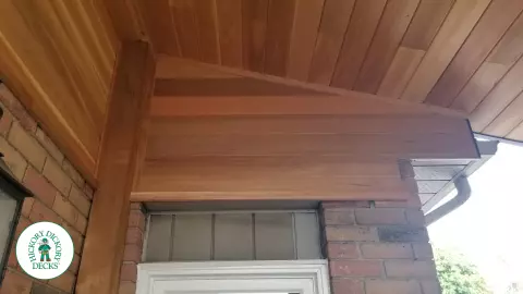 Low brown Veka deck with custom roof structure, black aluminum railing, and lights in steps.