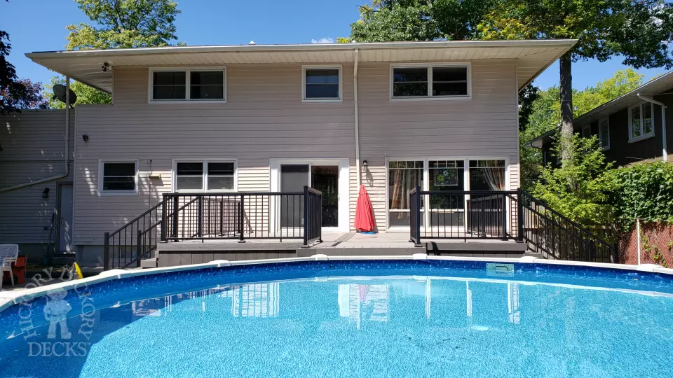 Grey above ground pool deck with black aluminum railings