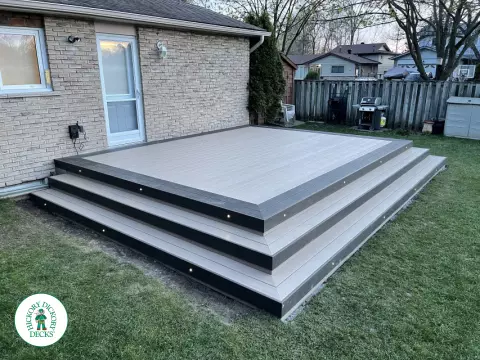 Grey clubhouse deck with wrap around stairs, lighting in steps, and a dark grey border.