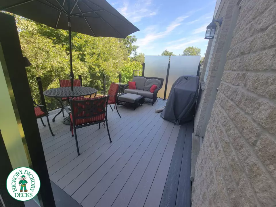 Multi level grey clubhouse deck with dark grey border and glass privacy screens on the top level.