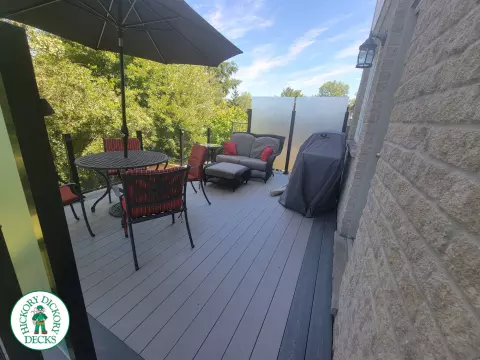 Multi level grey clubhouse deck with dark grey border and glass privacy screens on the top level.