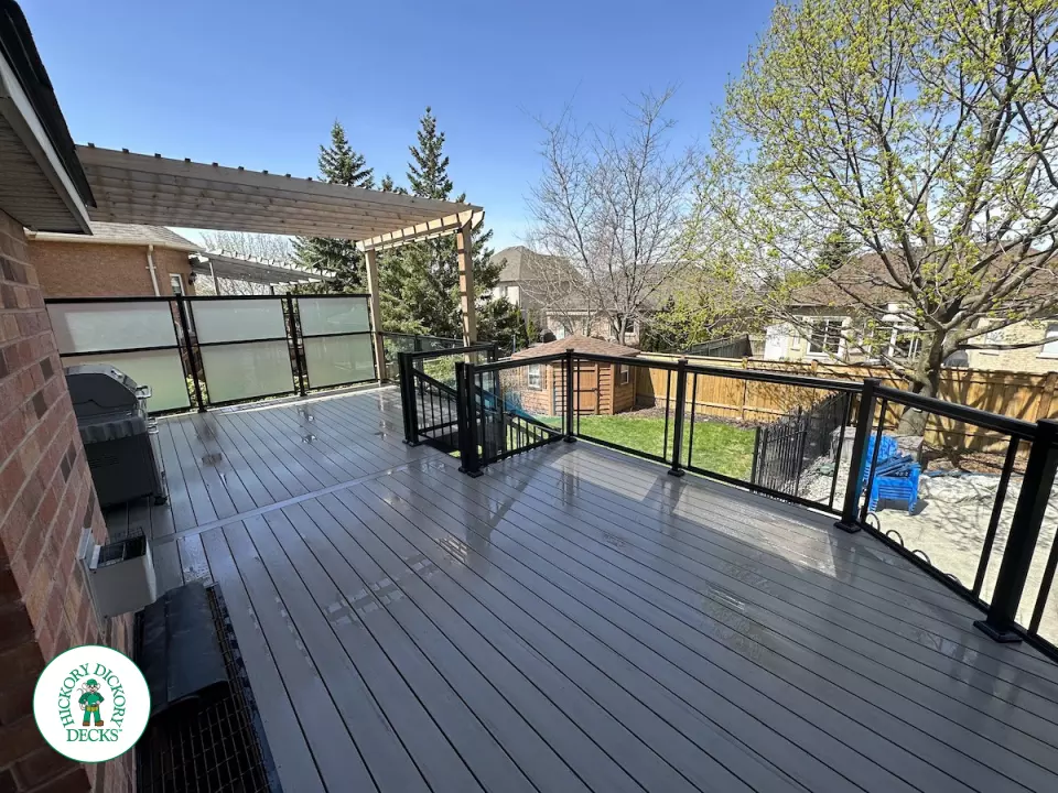 Large high deck with pergola, glass railing and frosted glass privacy screen.