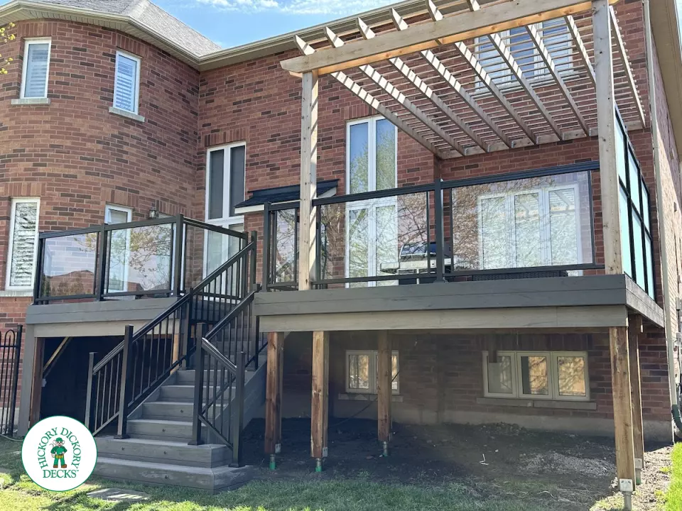 Large high deck with pergola, glass railing and frosted glass privacy screen.