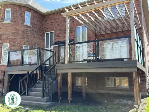 Large high deck with pergola, glass railing and frosted glass privacy screen.