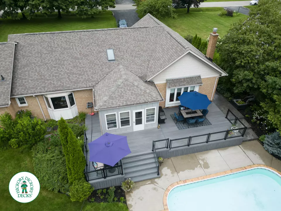 Large grey clubhouse deck with multi levels, lights in the steps, and glass railings.