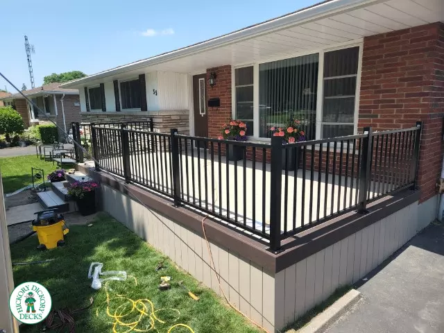 Large front porch in clay with a dark brown border and aluminum railings.