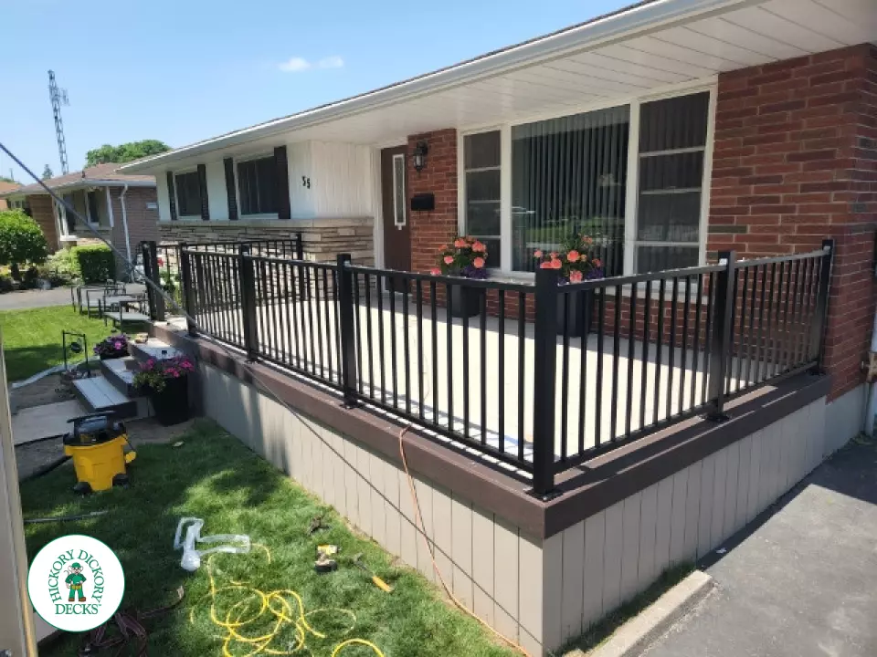 Large front porch in clay with a dark brown border and aluminum railings.