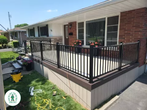 Large front porch in clay with a dark brown border and aluminum railings.