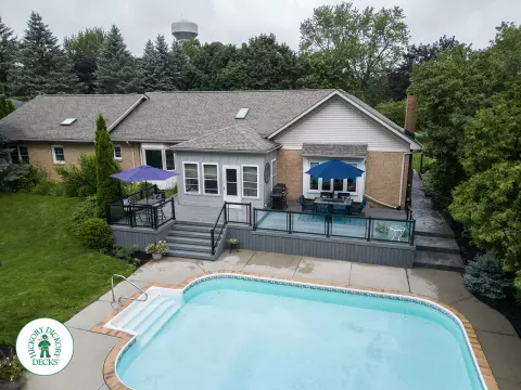 Large grey clubhouse deck with multi levels, lights in the steps, and glass railings.