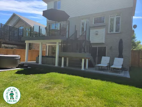Multi level grey clubhouse deck with dark grey border and glass privacy screens on the top level.