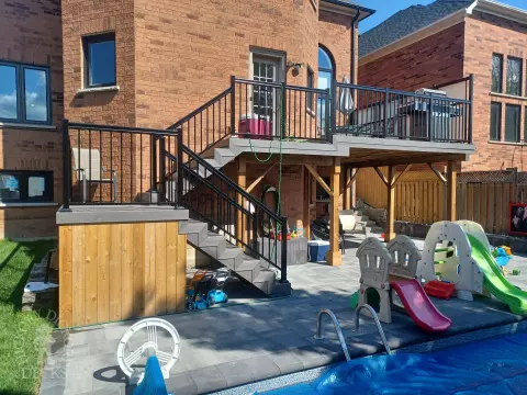 Large multi level grey composite deck with cedar skirt and black aluminum railing.