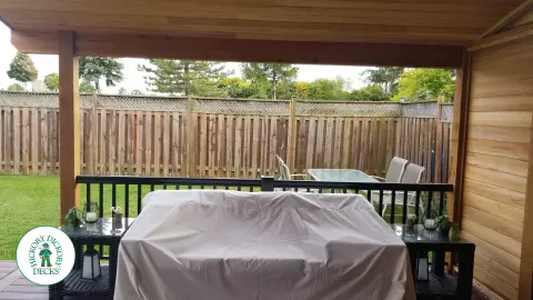 Low brown Veka deck with custom roof structure, black aluminum railing, and lights in steps.