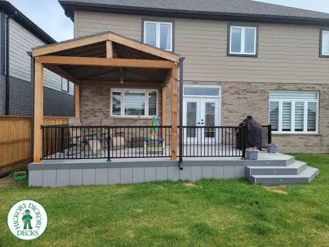 Large grey clubhouse deck with black aluminum railing and a custom cedar roof structure