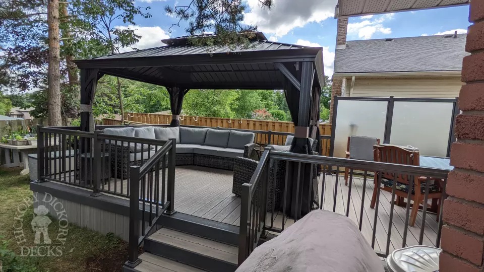 Grey composite walk out deck with dark grey borders, stained glass privacy screens, and aluminum style railing.