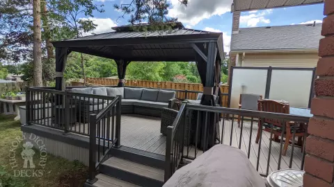 Grey composite walk out deck with dark grey borders, stained glass privacy screens, and aluminum style railing.