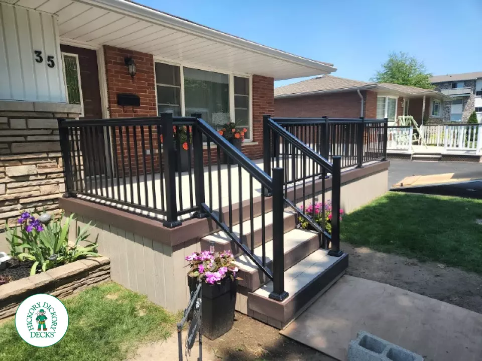 Large front porch in clay with a dark brown border and aluminum railings.
