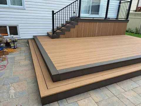 Multi level brown deck with glass railing, and a dark brown border.