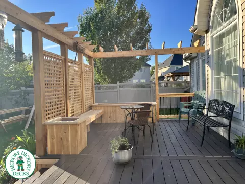 Mid size clubhouse deck in brown with cedar skirt, benches, planters, and a pergola.