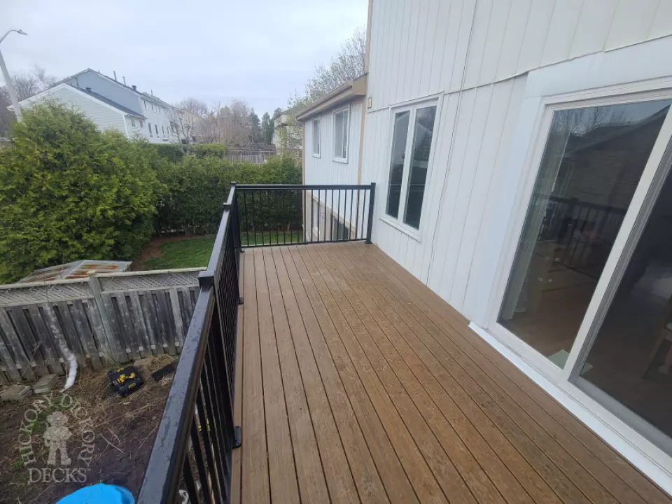 Dark brown Trex balcony with black aluminum railing.