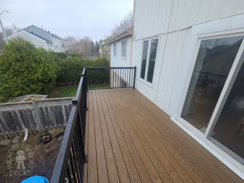 Dark brown Trex balcony with black aluminum railing.