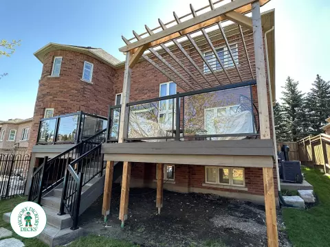 Large high deck with pergola, glass railing and frosted glass privacy screen.