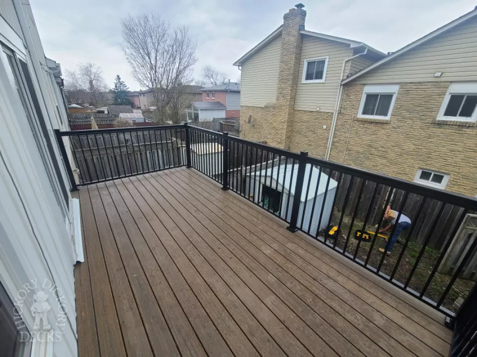 Dark brown Trex balcony with black aluminum railing.