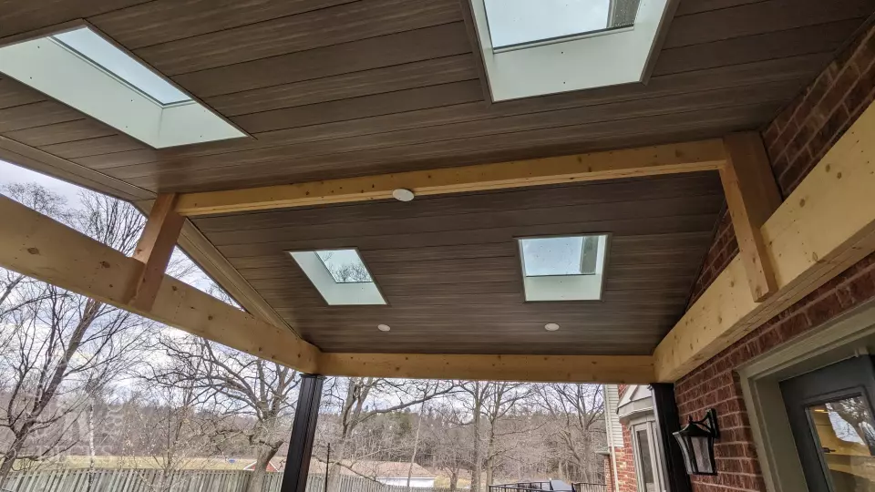 Large high Fiberon deck in brown. Glass railings and skylights in the custom roof structure.