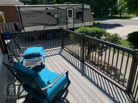 Grey front porch with brown trim and brown aluminum railing.