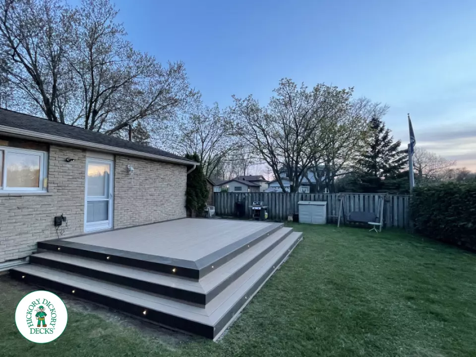 Grey clubhouse deck with wrap around stairs, lighting in steps, and a dark grey border.