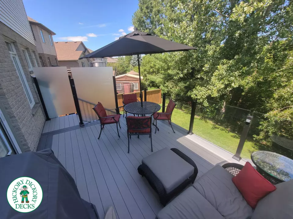Multi level grey clubhouse deck with dark grey border and glass privacy screens on the top level.