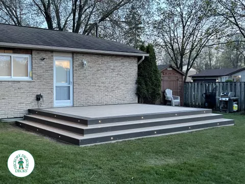 Grey clubhouse deck with wrap around stairs, lighting in steps, and a dark grey border.