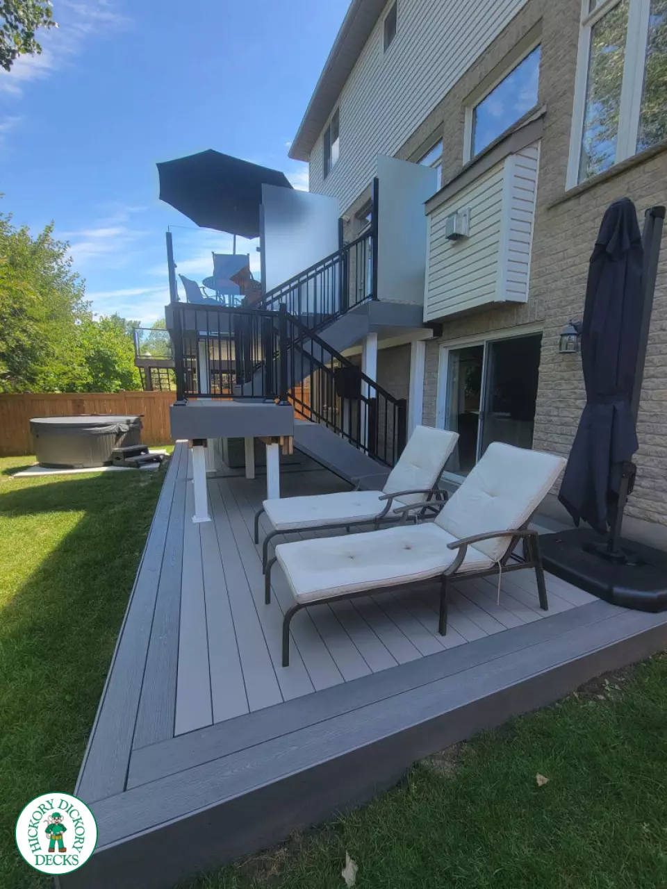 Multi level grey clubhouse deck with dark grey border and glass privacy screens on the top level.