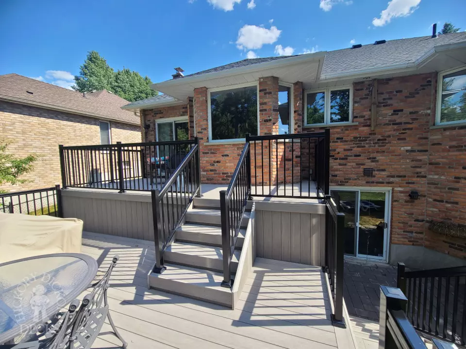 2 level grey composite deck with black aluminum railing.