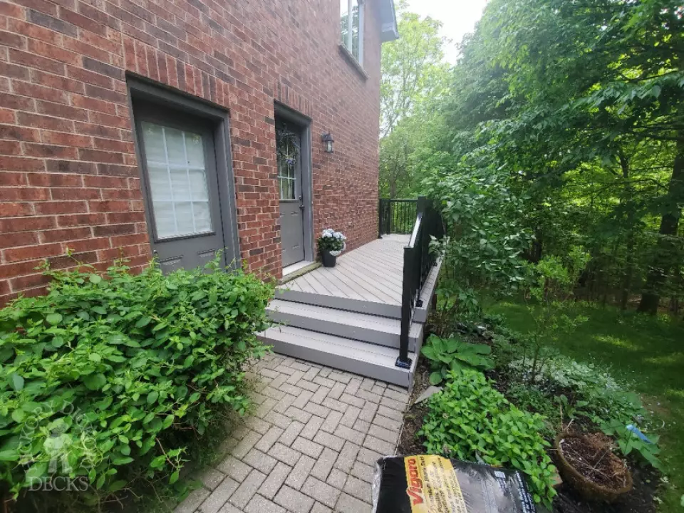 Small grey mid-rise composite deck with cedar posts.