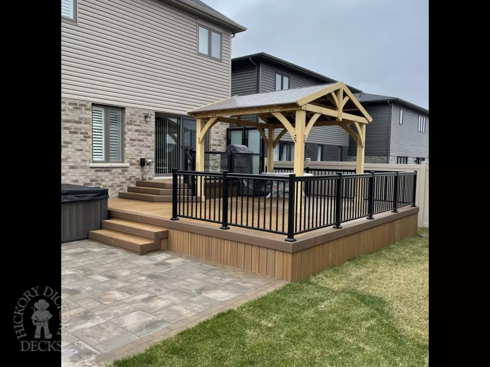 Brown composite deck with a roof structure, glass railings, access to the hot tub, and frosted glass privacy screens.