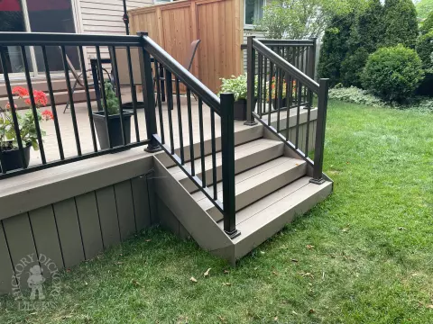 Small CLubhouse deck with four steps leading to backyard, black aluminum railing, and a cedar privacy screen.