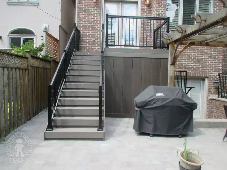 Elevated grey clubhouse deck with black aluminum railing and lights in steps.